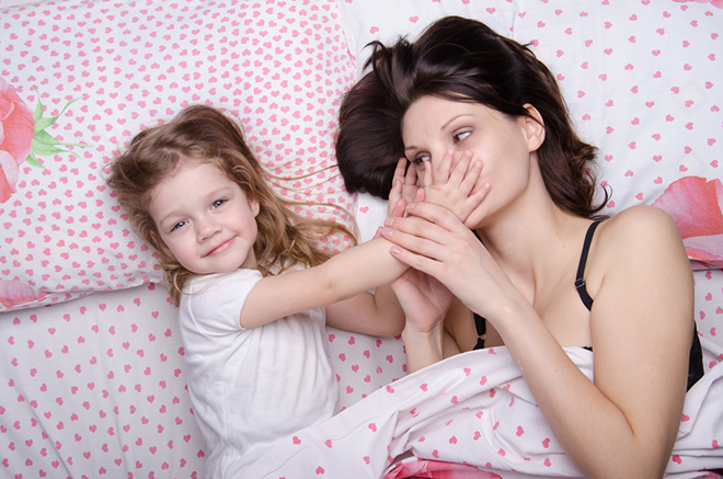 Mom and daughter with an excellent mood lie in bed